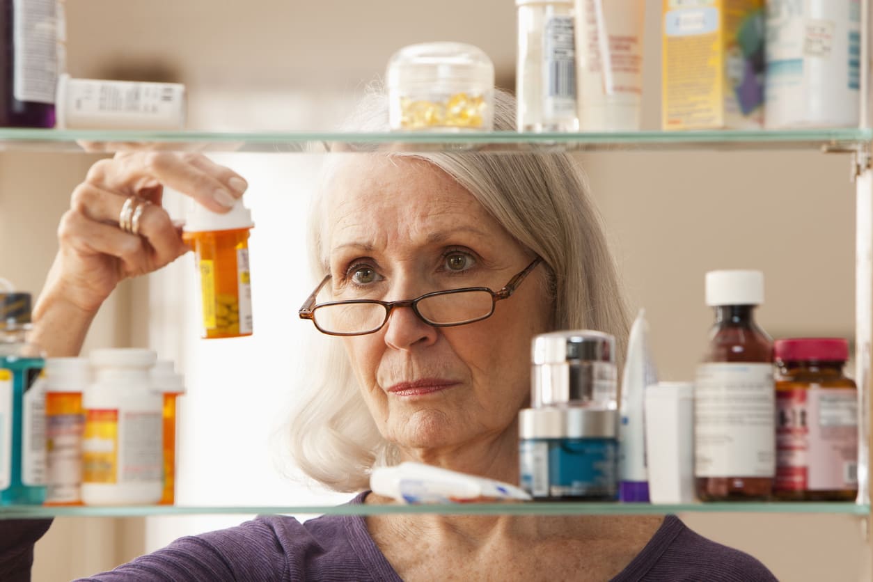 Frau schaut sich die Medikamente in ihrer Hausapotheke an.