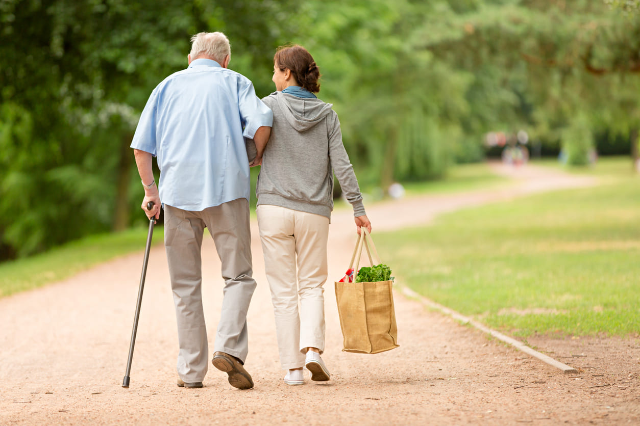 Pflegerin hilft pflegebedürftigem Senioren beim Einkauf