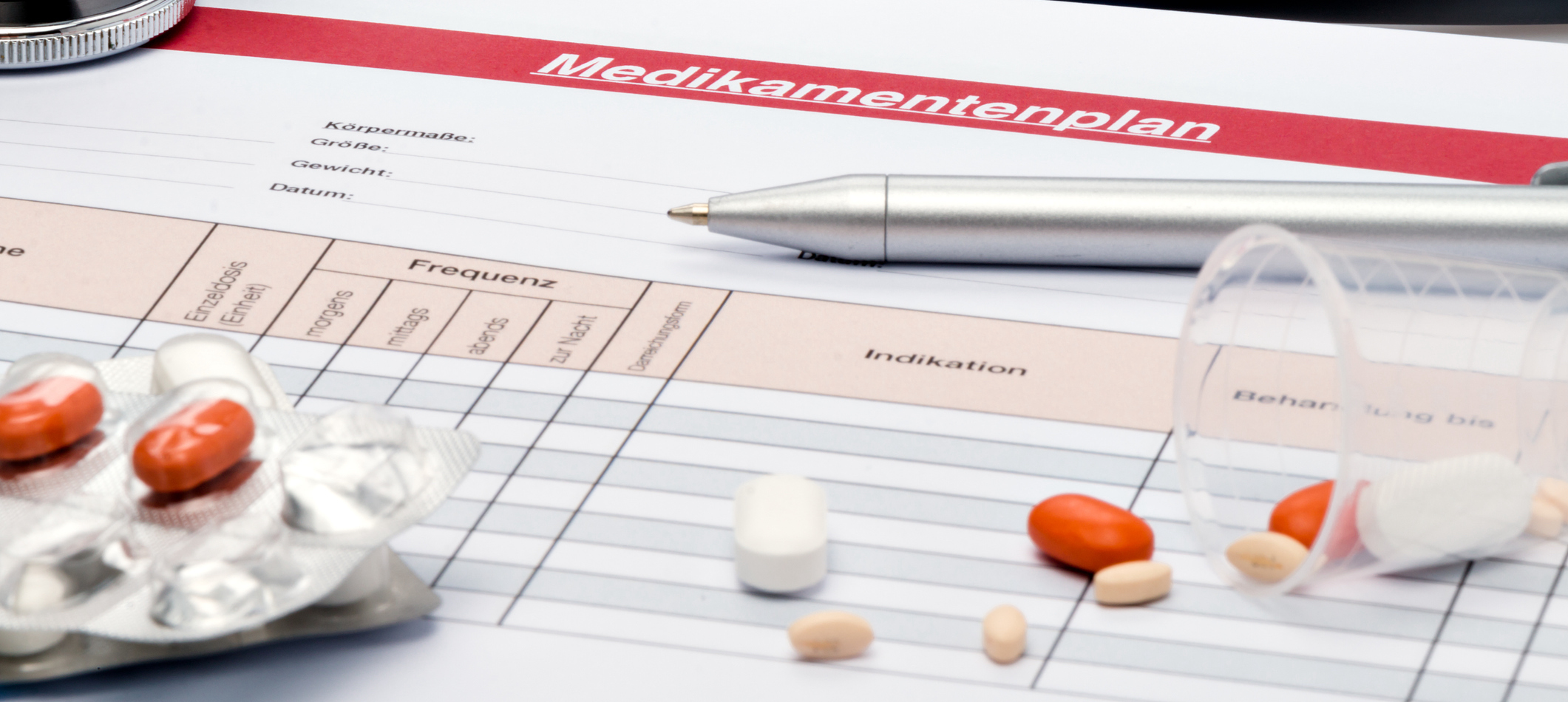 Ein Medikationsplan liegt auf einem Tisch zusammen, zusammen mit Pillen. Das Bild symbolisiert die Leichtigkeit, mit der hellomed auf Änderungen bei der Medikation reagieren kann